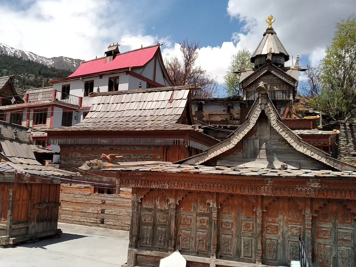 Shree Narayan Nagin Devi Ji Mandir at Kalpa during partly cloudy skies, featuring wooden temples intricate carvings snowy peaks, perfect cultural experience Kinnaur tour package.