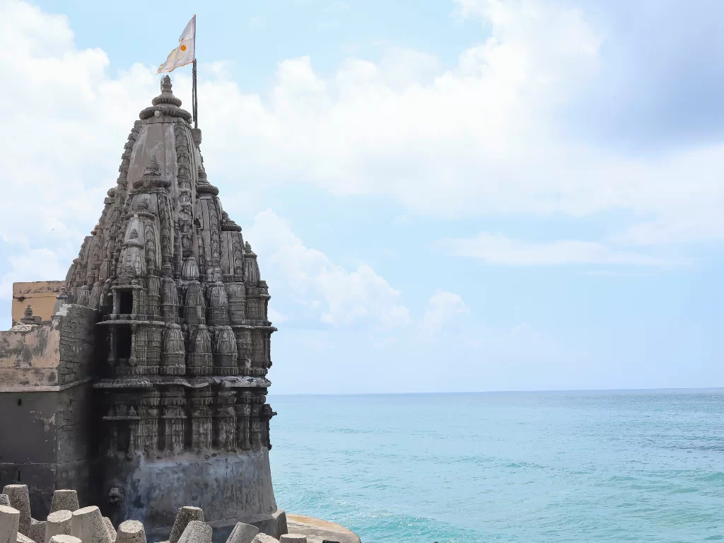 Shree Samudra Narayan Temple in Dwarka during clear day, featuring multi-tiered shikhara with flag overlooking Arabian Sea, perfect pilgrimage experience with Gujarat tour packages.