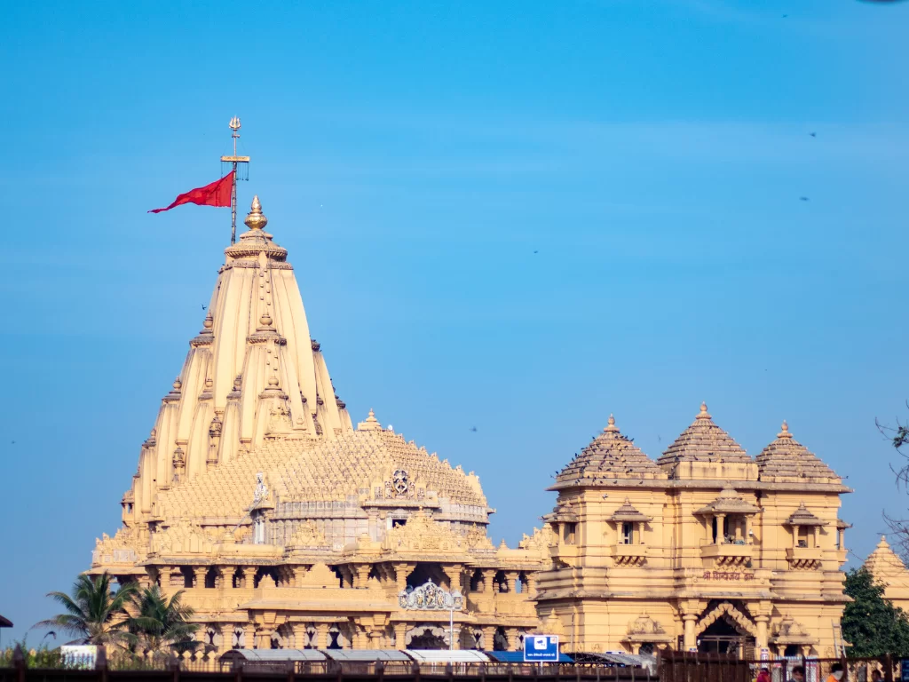 Shree Somnath Jyotirlinga Temple at Prabhas Patan during clear day, featuring shikhara with saffron flag, intricate carvings, domes, perfect pilgrimage experience with Gujarat tour packages.
