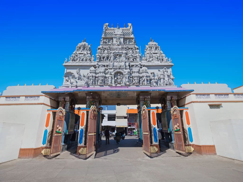 Shree Annapurna Temple at Indore during clear daylight, featuring ornate white gopuram entrance orange pillars, perfect spiritual experience Madhya Pradesh tour package.