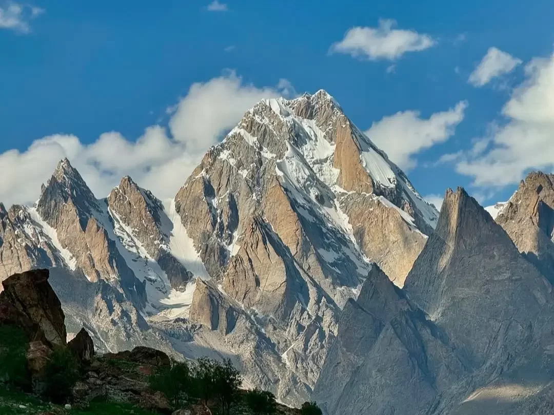 Majestic snow-peaked Karakoram mountains near Siachen Base Camp Ladakh under partly cloudy sky, featuring sharp ridges, rocky foreground, perfect adventure Siachen tour package.