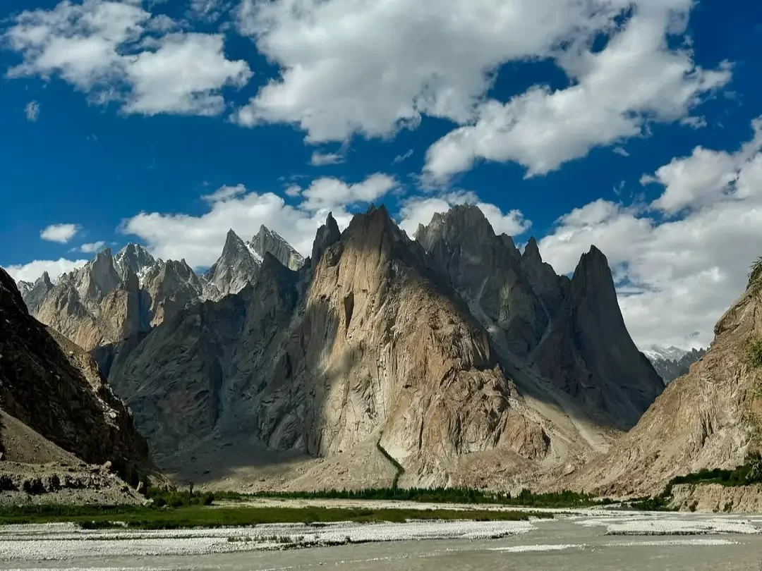 Towering Karakoram mountain range near Siachen Base Camp Ladakh during partly cloudy day, featuring glacier valley, riverbed, perfect trekking Siachen tour package.