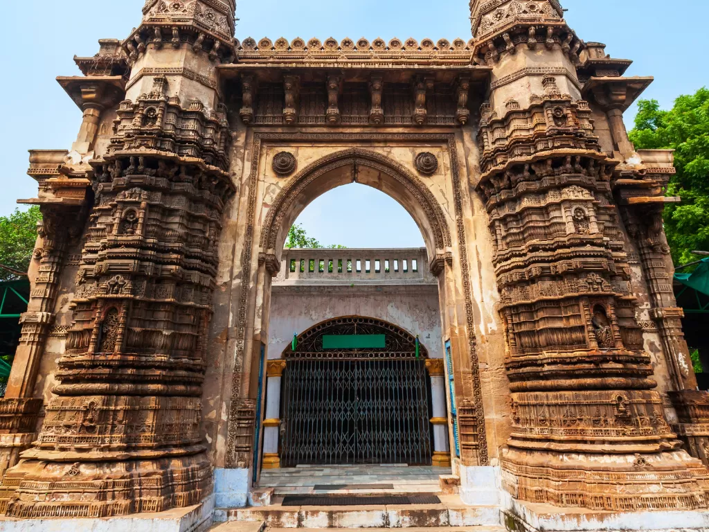 Jhulta Minar gateway at Sidi Bashir Mosque Ahmedabad during daylight, featuring carved towers and arched entrance, perfect cultural Gujarat tour package.