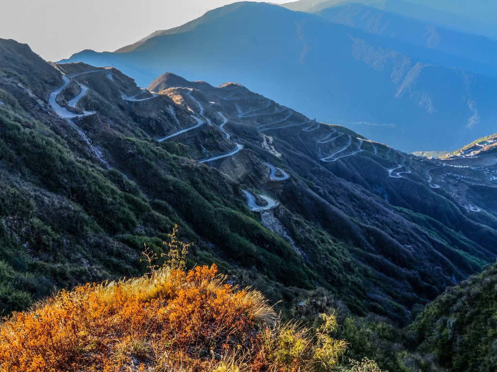 Silk Route Zuluk Sikkim during golden hour, featuring winding mountain roads deep valleys, perfect road trip adventure Sikkim tour package. ​