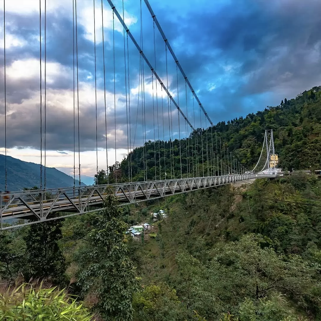 Singshore Bridge Pelling in blue hour sky, spanning deep green valley and village below, perfect adventure Sikkim tour package.