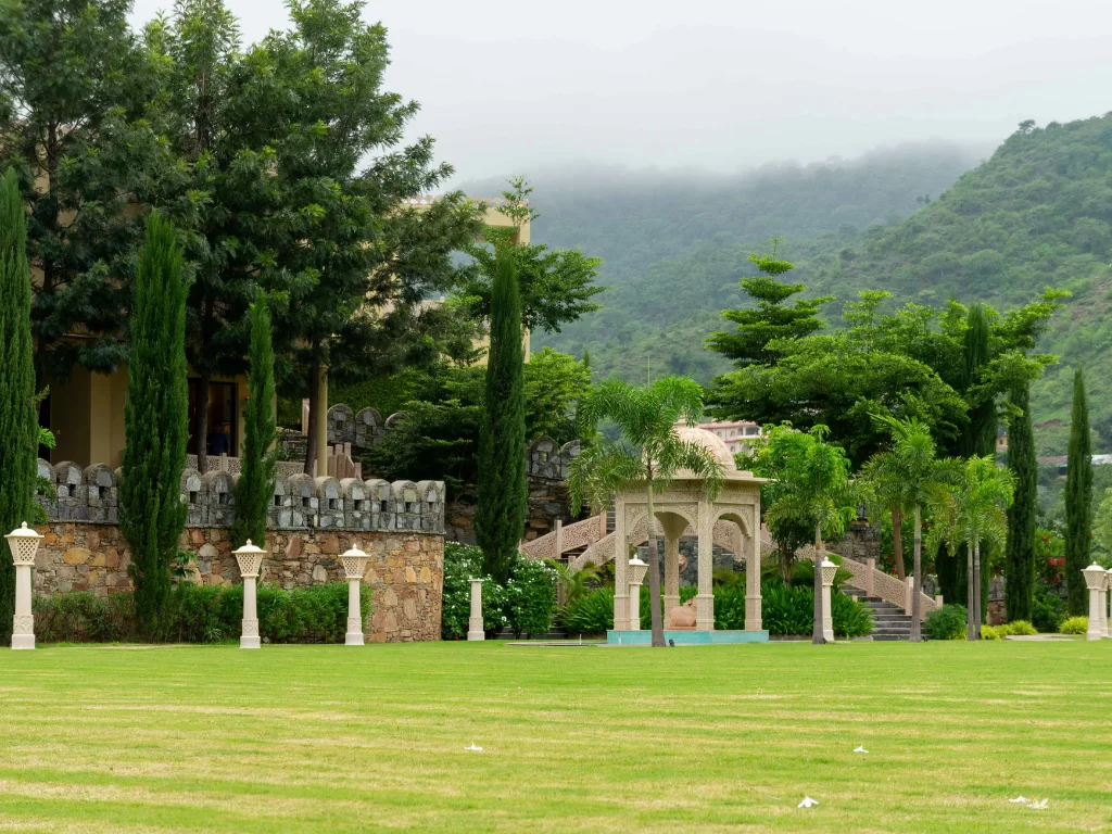 Sisodia Rani ka Bagh Jaipur lush green lawns tiered white marble pavilion fountains cypress palms misty Aravalli hills, Rajasthan Tour Packages.