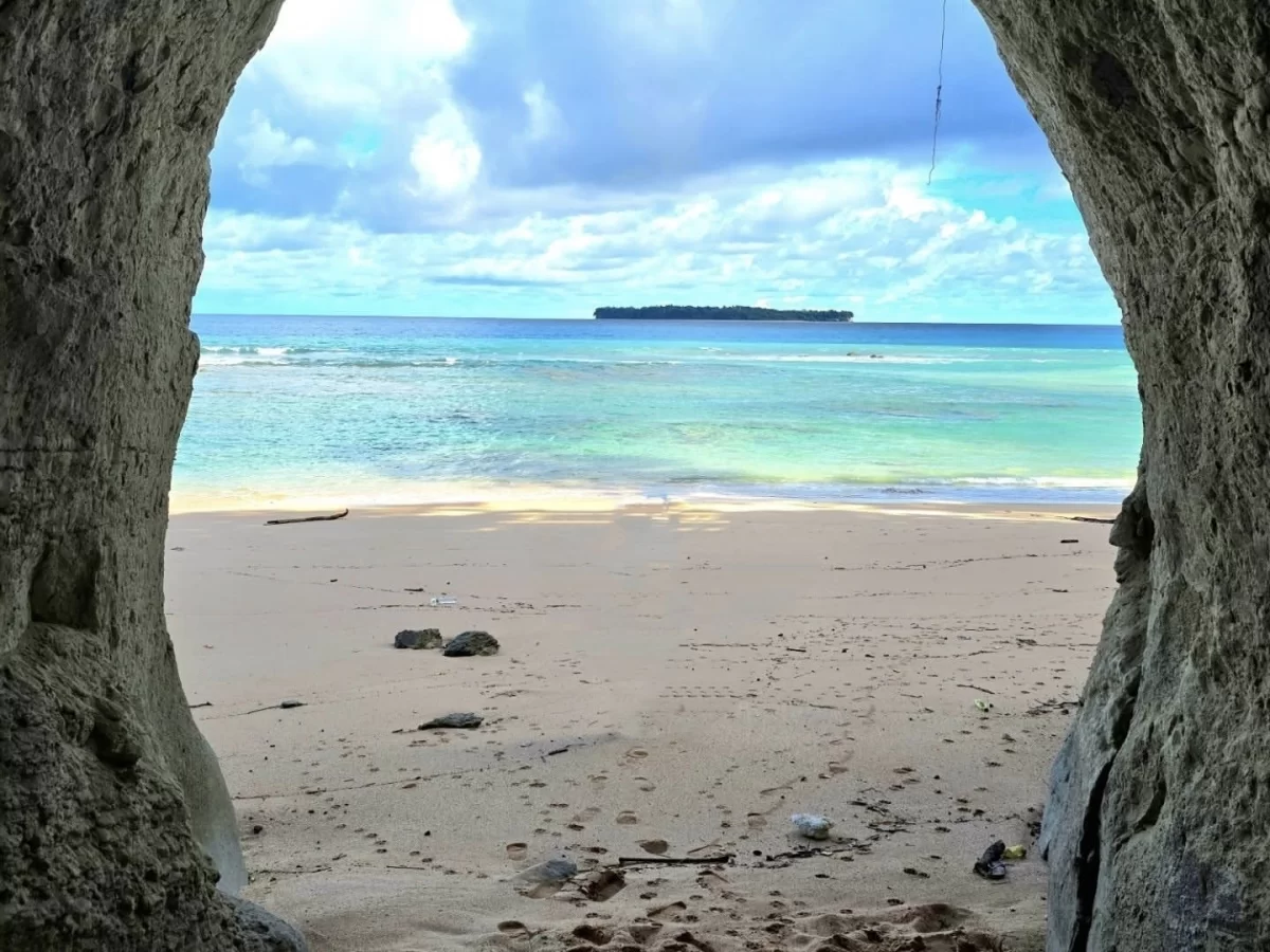 Cave view of Sitapur Beach in Neil Island at midday, featuring turquoise sea and distant island, perfect Andaman tour package