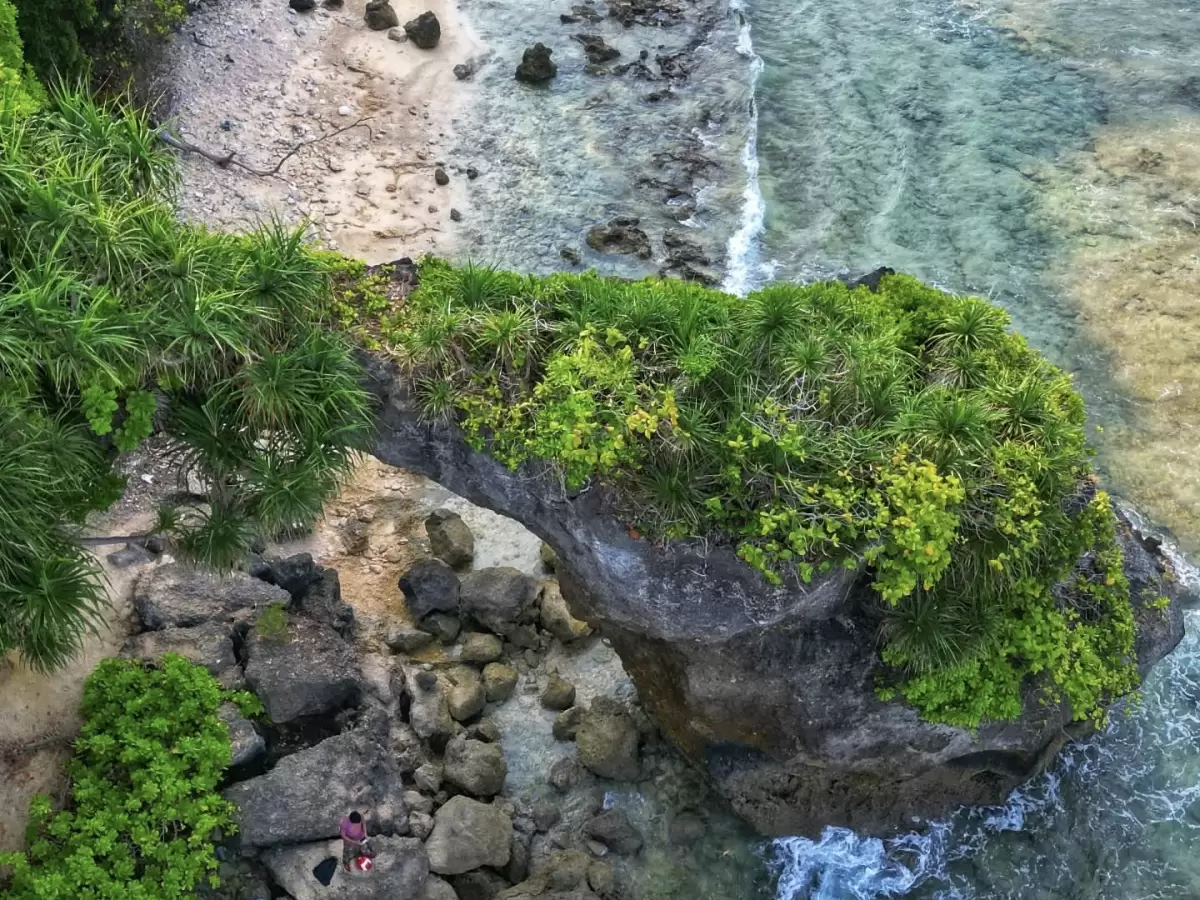 Rocky arch viewpoint at Sitapur Beach in Neil Island, featuring green cliffs and clear sea, perfect Andaman sightseeing tour package.