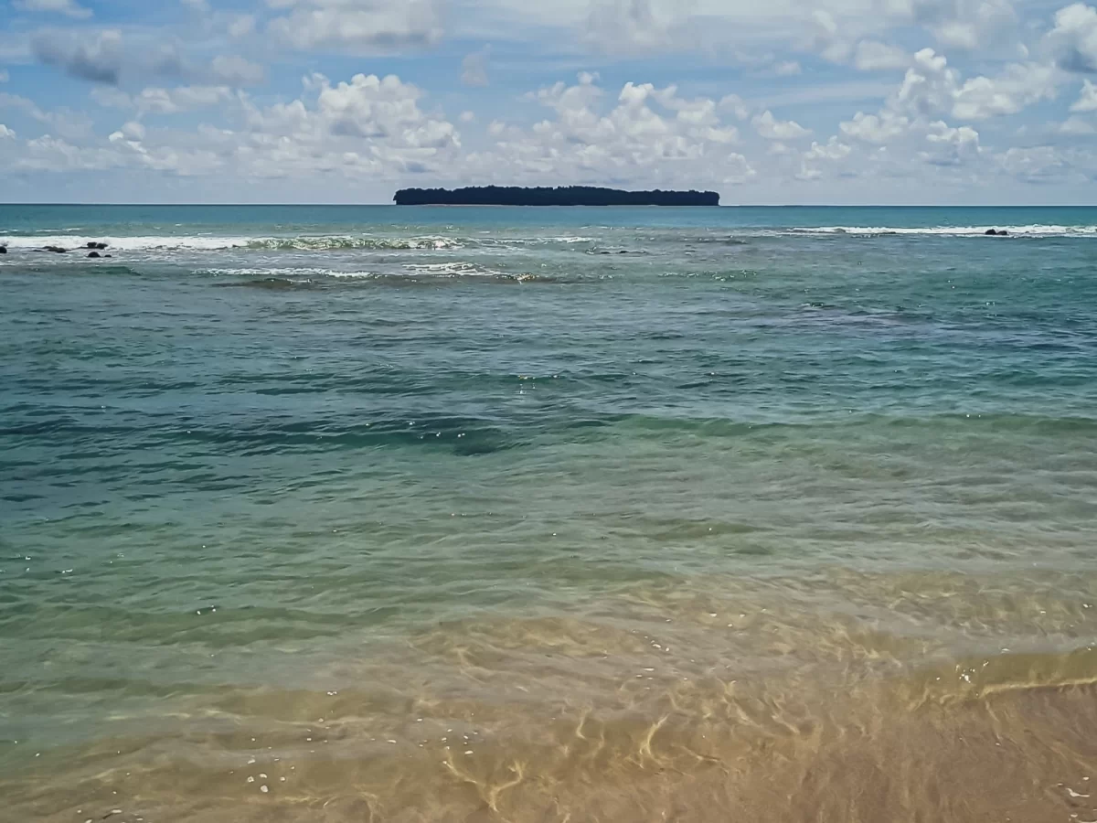 Clear waters at Sitapur Beach in Neil Island at midday, featuring distant island and gentle waves, perfect Andaman beach tour package