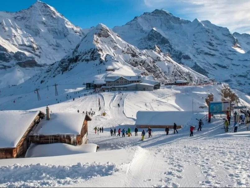 Skiers at Skiing Point Narkanda during winter sunny day, featuring snowy slopes, Himalayan peaks, cable car, chalets, perfect adventure Himachal Pradesh tour package.