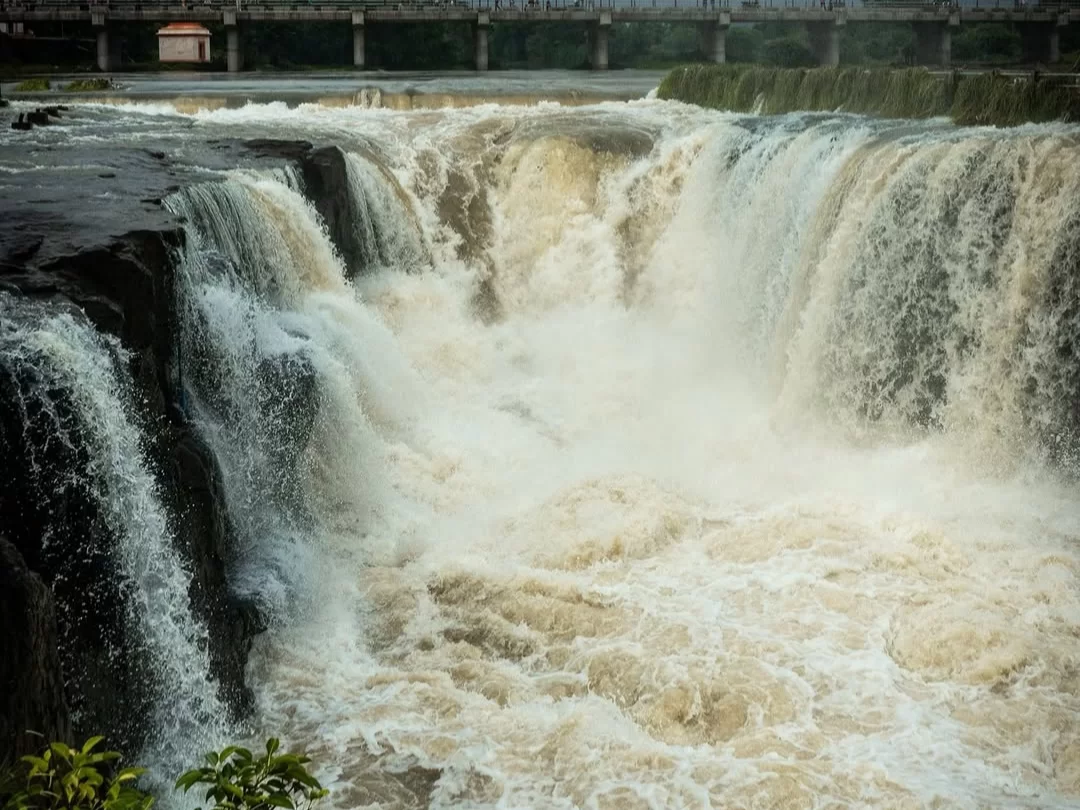 Powerful Someshwar Waterfall in Nashik Maharashtra with wide cascading waters and bridge visible above the rocky riverbed