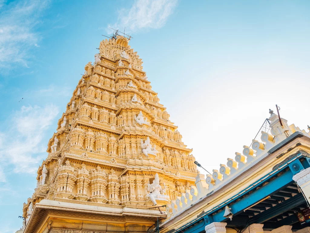 Gopuram of Sri Chamundeshwari Temple in Mysore during clear evening, featuring ornate golden tower and blue sky, perfect Karnataka tour package