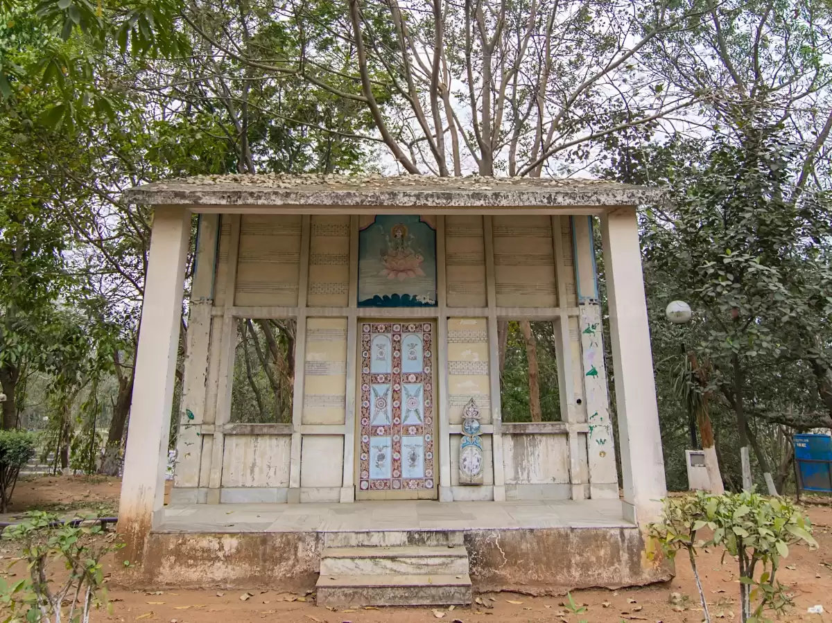 Namghar temple at Srimanta Sankardev Kalakshetra Guwahati during sunny day, featuring Lakshmi Devi idol carved doors trees, perfect cultural experience Assam tour package.