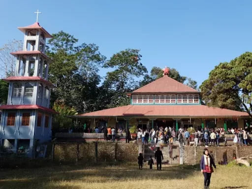 St. Teresa’s Church in Kalimpong, West Bengal, featuring its distinctive hill-style architecture and bell tower with visitors gathered in the courtyard, a notable heritage landmark included in West Bengal tour packages.