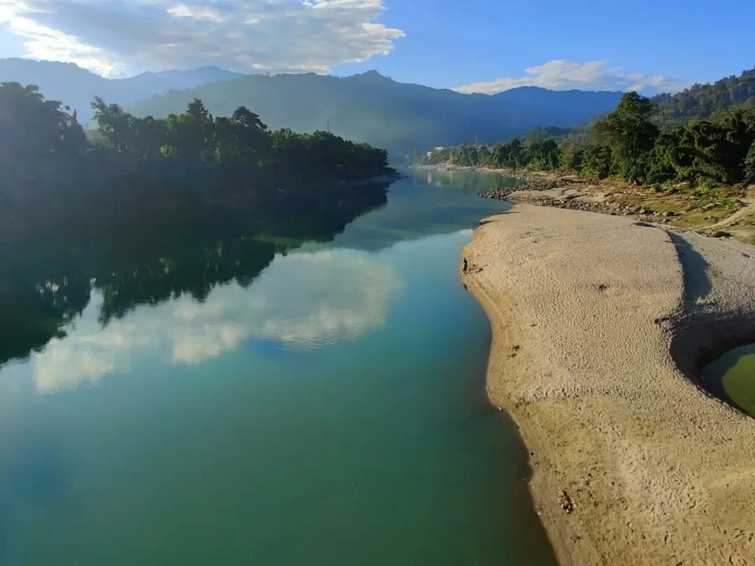 Subansiri River serene emerald waters flowing past sandy banks and forested hills in Arunachal Pradesh Tour Package.