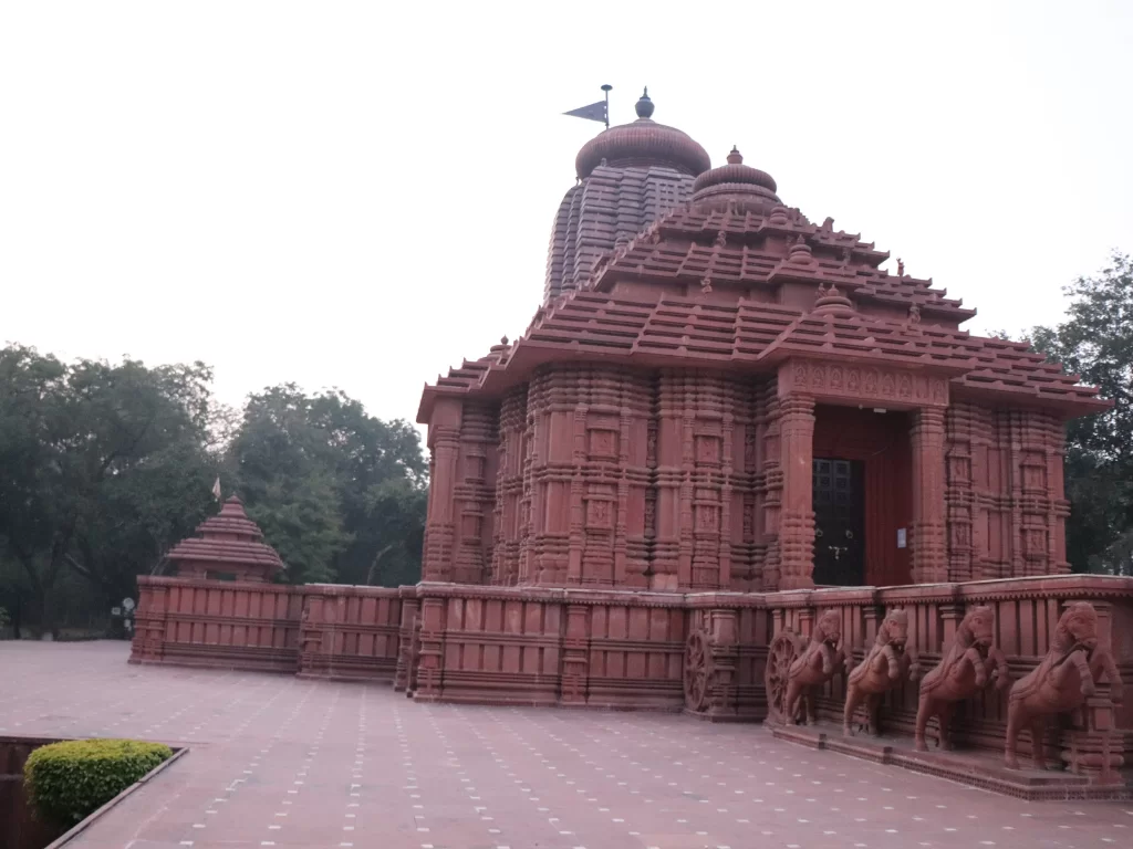 Sun Temple Gwalior during golden morning light, featuring towering rekha deul shikhara and ornate jagamohana with red sandstone carvings and flag atop, perfect heritage experience in Madhya Pradesh tour package.