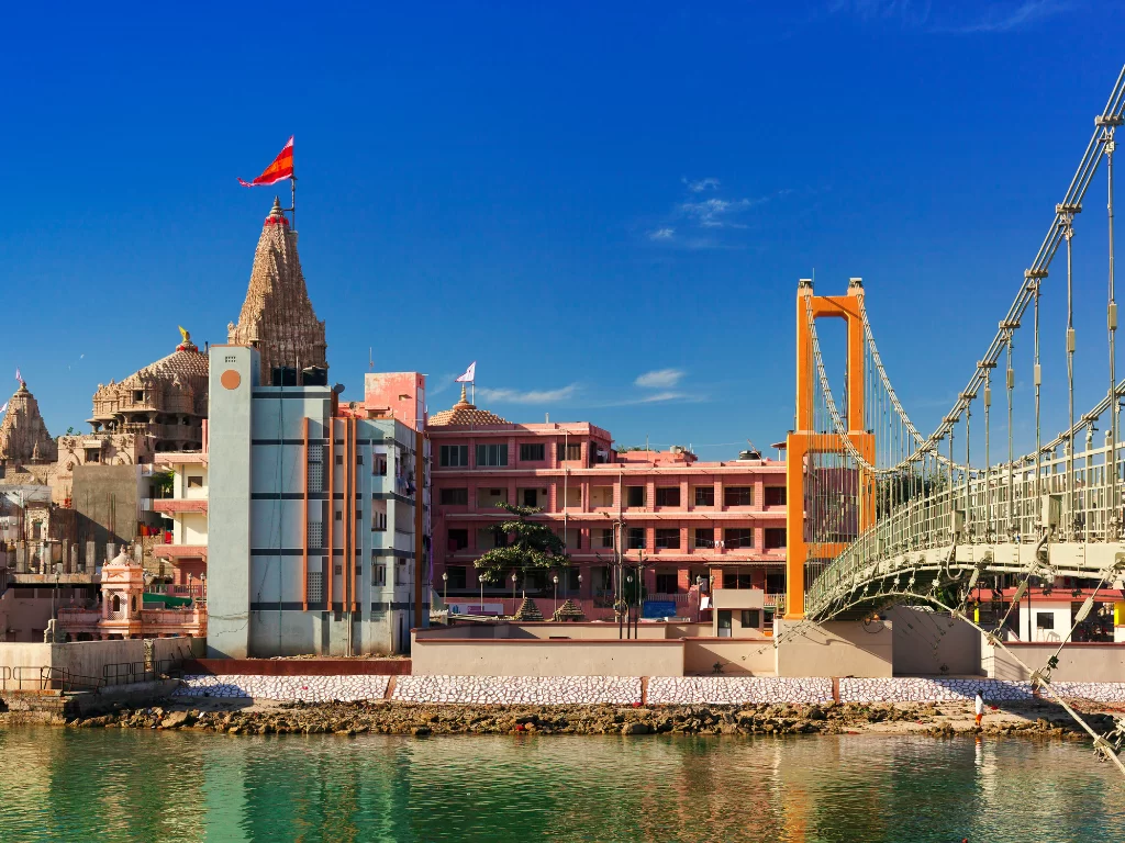 Sudama Setu suspension bridge in Dwarka during clear day, featuring orange cables over Gomti River with Dwarkadhish Temple views, perfect pilgrimage experience with Gujarat tour packages.