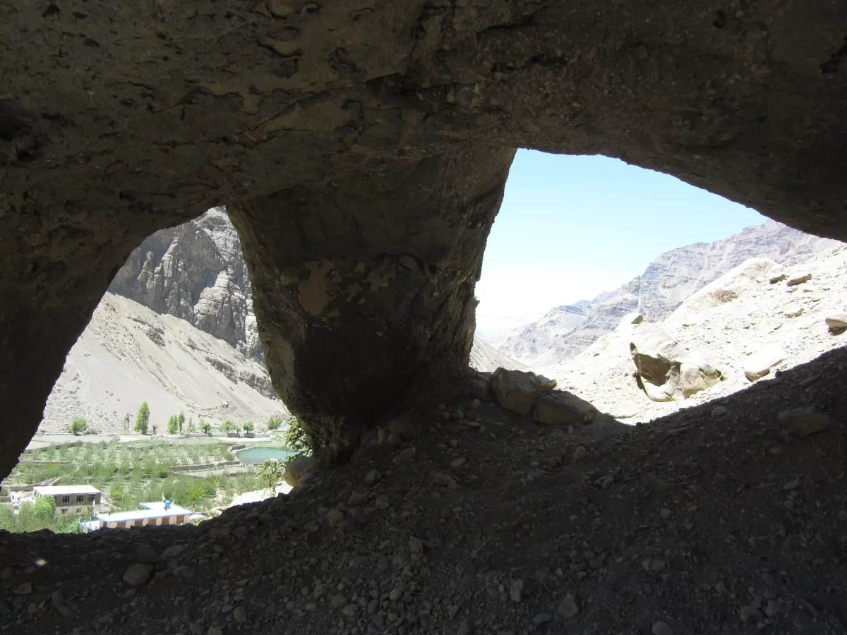 Tabo Caves framed view at Tabo Spiti Valley during clear skies, featuring Spiti River villages mountains through double cave openings, perfect adventure experience Spiti Valley Himachal tour package.