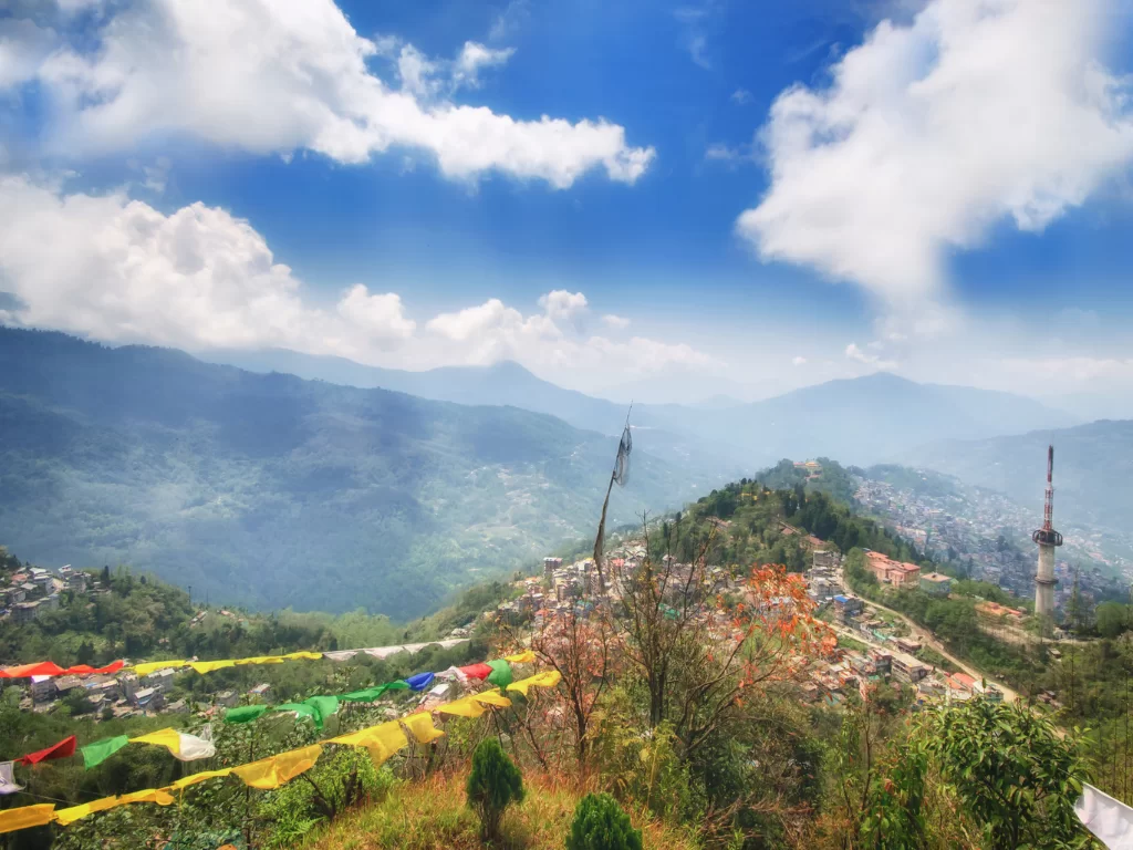 Tashi View Point Gangtok during clear skies, featuring prayer flags hillside town Himalaya views, perfect scenic sunrise experience Sikkim tour pack