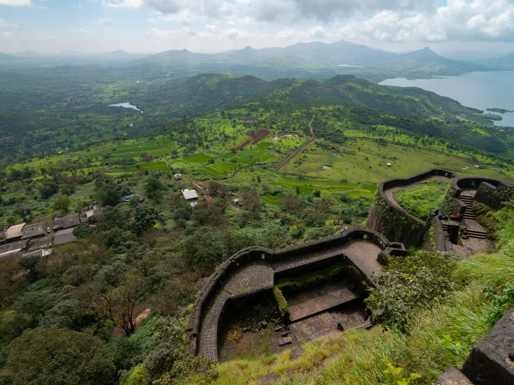 Tikona Fort Maharashtra panoramic green monsoon walls Pawna lake valleys, curved bastions villages Lohagad Korigad peaks Western Ghats, perfect Lonavala Maval forts trek package.