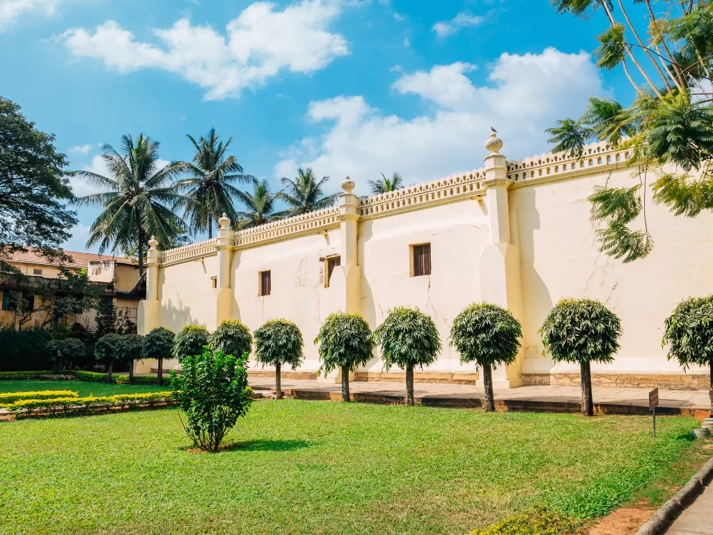 Tipu Sultan Summer Palace Bangalore sunny day, white walls pillars palms trees garden lawn, perfect Karnataka tour package.