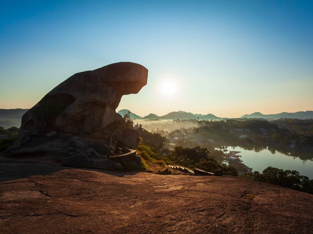 Toad Rock Sunset Point Mount Abu golden hour, featuring toad-shaped rock silhouetted against setting sun overlooking Nakki Lake town hazy hills, perfect Rajasthan hill station tour packages.