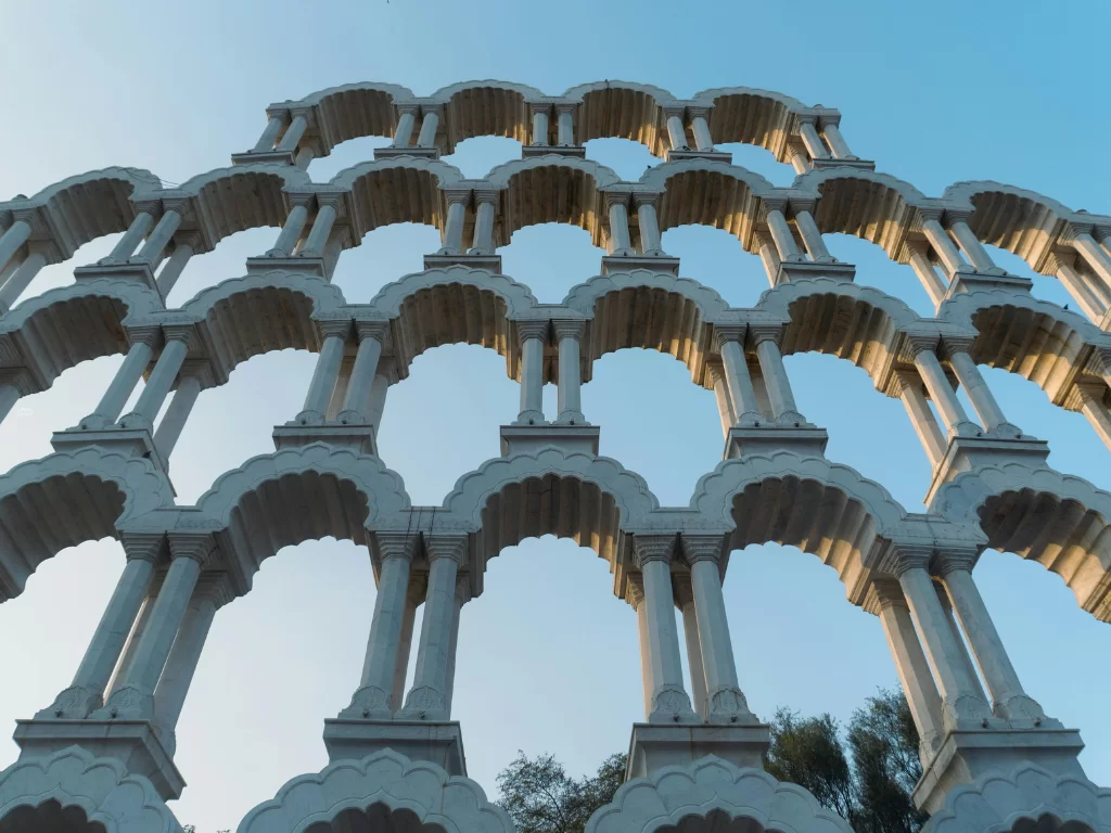 Toran Darwaza Jaipur towering multi-tiered white stone arches pillars grand gateway blue sky, Rajasthan Tour Packages.