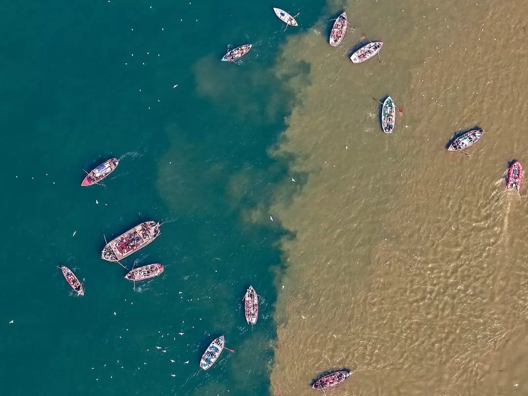 Triveni Sangam aerial view, scattered white boats green brown rivers meeting, perfect Uttar Pradesh tour package.