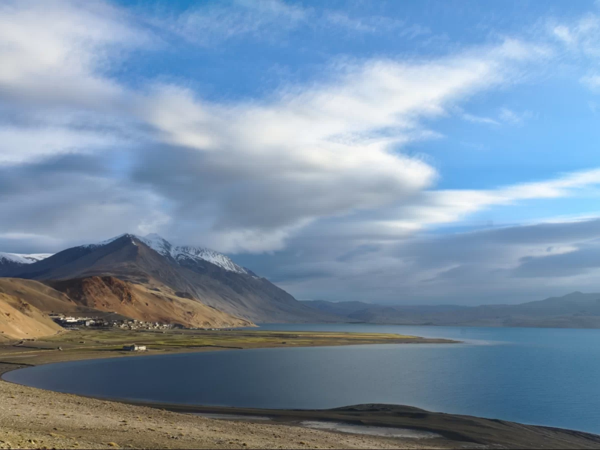 Tso Moriri Lake in Ladakh during partly cloudy skies, featuring snow mountains, villages, turquoise waters and barren shores, perfect serene adventure with Ladakh tour package.