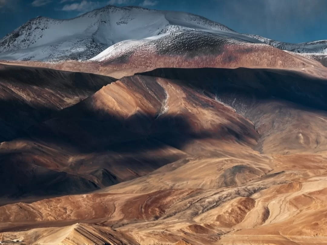 Rugged mountains near Tso Moriri in Ladakh during partly cloudy day, featuring snow peaks and barren ochre valleys, perfect trekking adventure with Ladakh tour package.