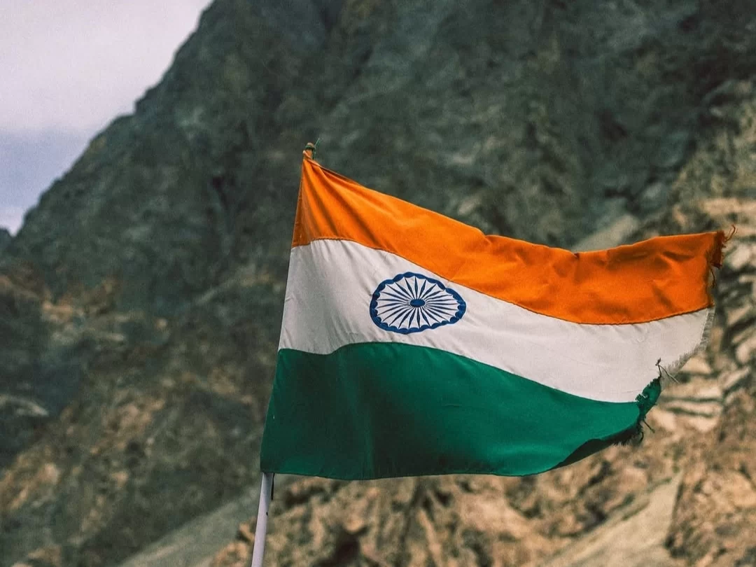 Indian Tricolour flag proudly fluttering against majestic Karakoram mountains in Turtuk Nubra Valley Ladakh near Pakistan border, symbolizing national pride, perfect patriotic high-altitude adventure with Ladakh tour package. 