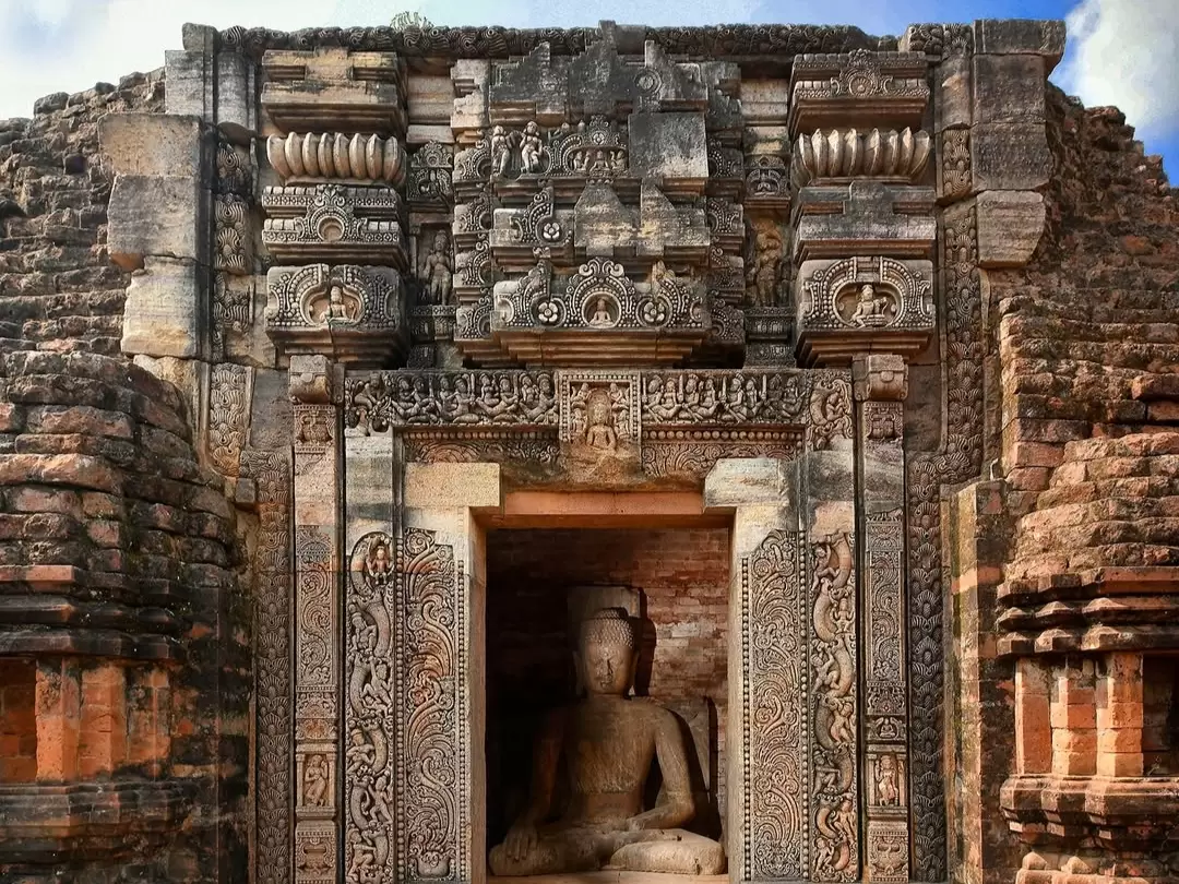 Udayagiri Caves in Sanchi, Madhya Pradesh with intricately carved sandstone entrance and seated Buddha statue, featured in Madhya Pradesh tour packages