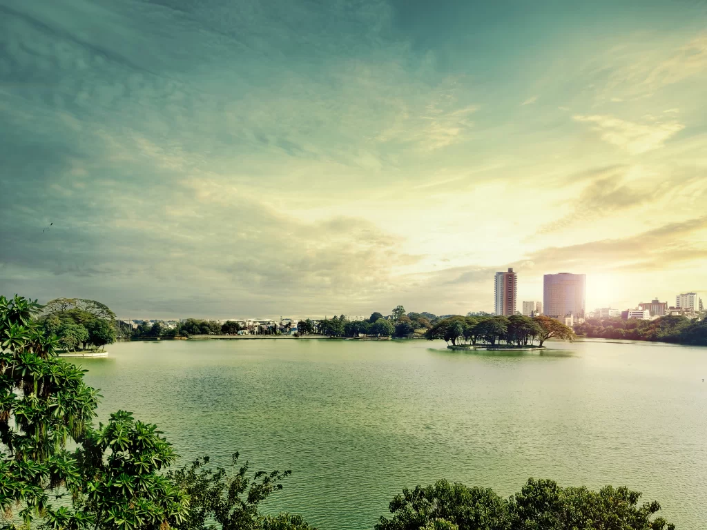 Ulsoor Lake Bangalore golden hour, serene lake trees island highrises skyline, perfect Karnataka tour package.