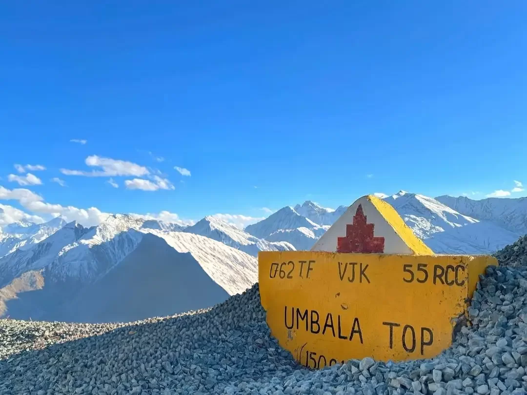 Umba La Pass Umbala Top Ladakh yellow army signboard 062 TF VJK 55 RCC snowy Himalayan peaks blue sky clouds gravel foreground; rugged Kargil Drass Suru adventure photography package.