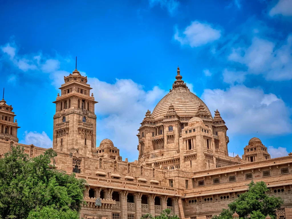 Umaid Bhawan Palace at Jodhpur during sunny day, featuring golden domes, minarets, Art Deco architecture, perfect romantic experience Rajasthan tour packages.