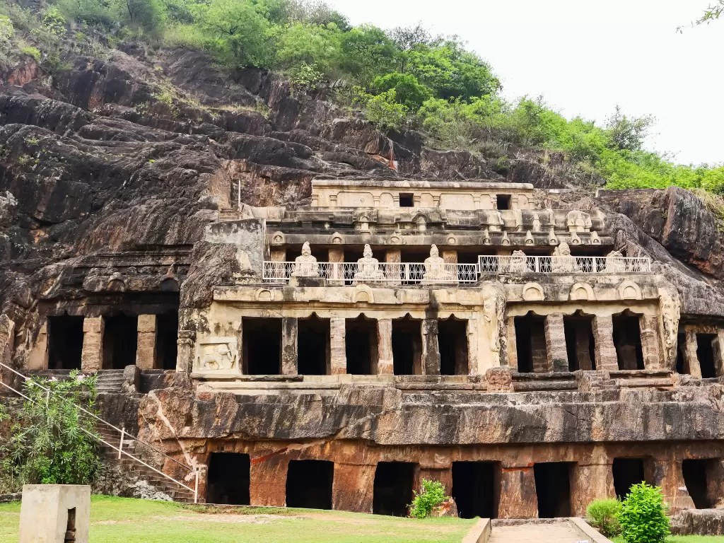 Undavalli Caves at Vijayawada during clear weather, featuring rock-cut facade and green hills, perfect cultural experience Andhra Pradesh tour package.