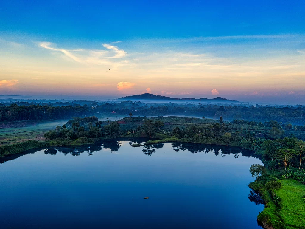 Valvan Lake View Point sunrise aerial panorama misty tropical lake surrounded by lush green hills rice fields distant mountains blue skies, perfect Lonavala Maharashtra nature tour packages. 