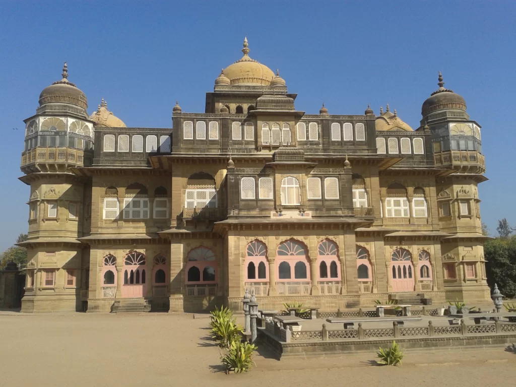 Vijaya Vilas Palace at Mandvi Kutch during clear sunny day, featuring golden domes, pink arches, jharokas and sandstone carvings, perfect royal heritage experience with Gujarat tour packages.
