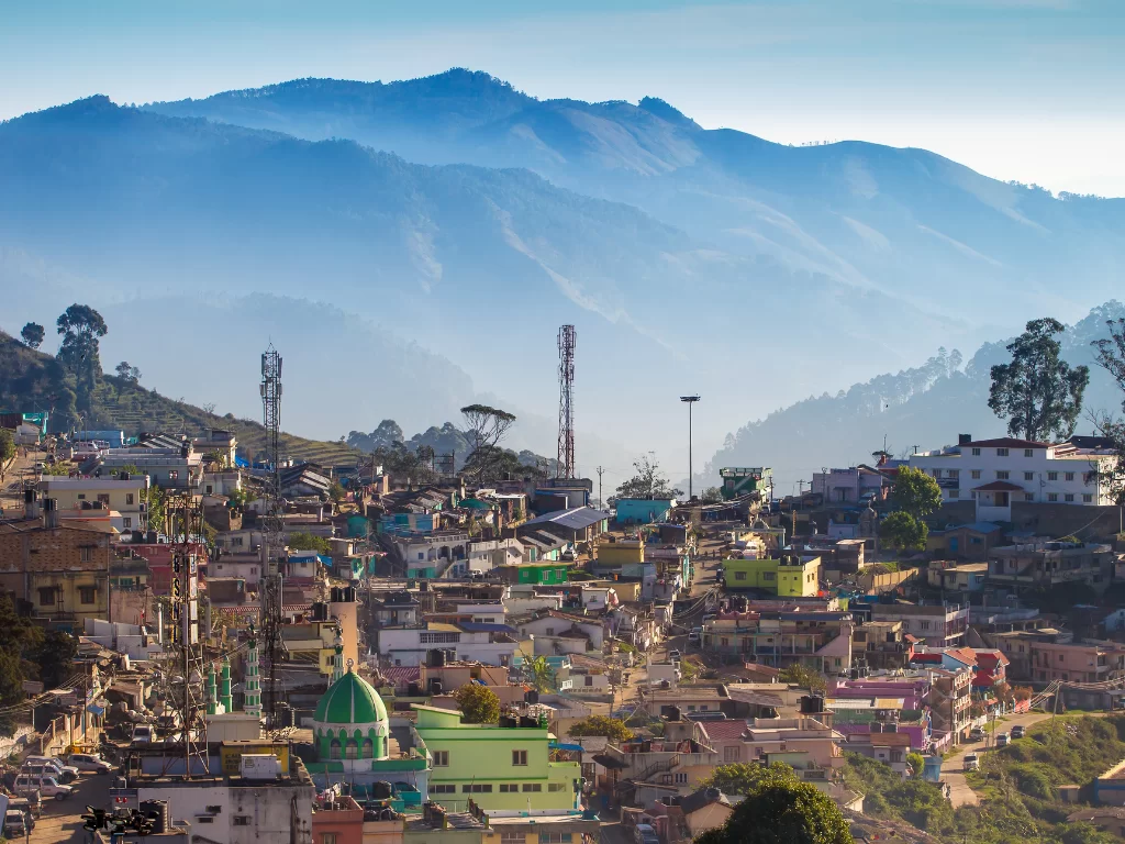 Poombarai village near Kodaikanal, featuring colourful hillside houses, communication towers and layered blue mountains, perfect offbeat Tamil Nadu tour package