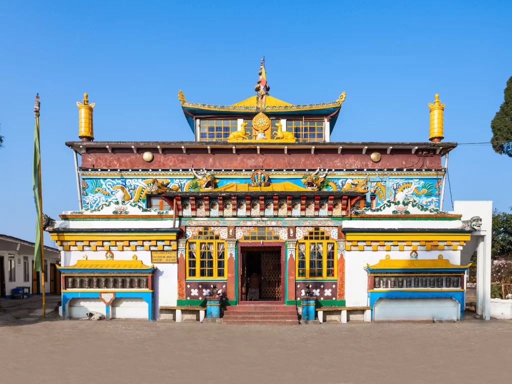 Yiga Choeling Monastery in Darjeeling during sunny daytime, featuring colorful Tibetan facade and prayer flags, perfect spiritual Darjeeling tour package
