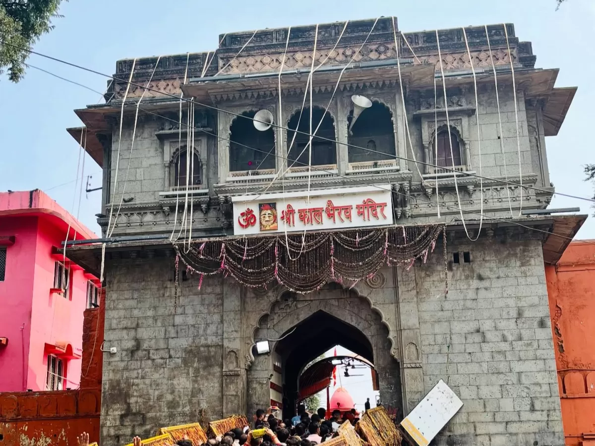 Shree Kaal Bhairav Temple gate at Ujjain during clear daylight, featuring stone archway Om banner garlands devotees, perfect spiritual Madhya Pradesh tour package.