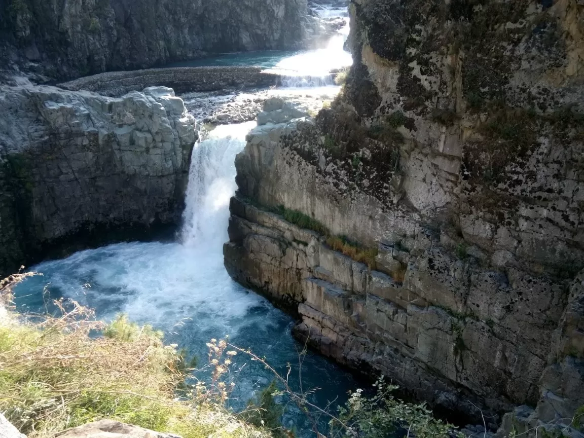 Dramatic Aharbal Waterfall Kashmir sunlight cascade gorge, roaring turquoise pool rugged cliffs grassy edges, perfect Jammu Kashmir scenic nature waterfall adventure package.