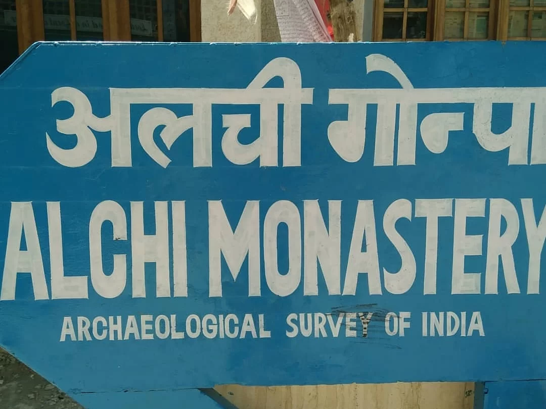 Alchi Gompa signboard during clear day, featuring Hindi/English text by Archaeological Survey of India, perfect heritage experience for Ladakh tour package.