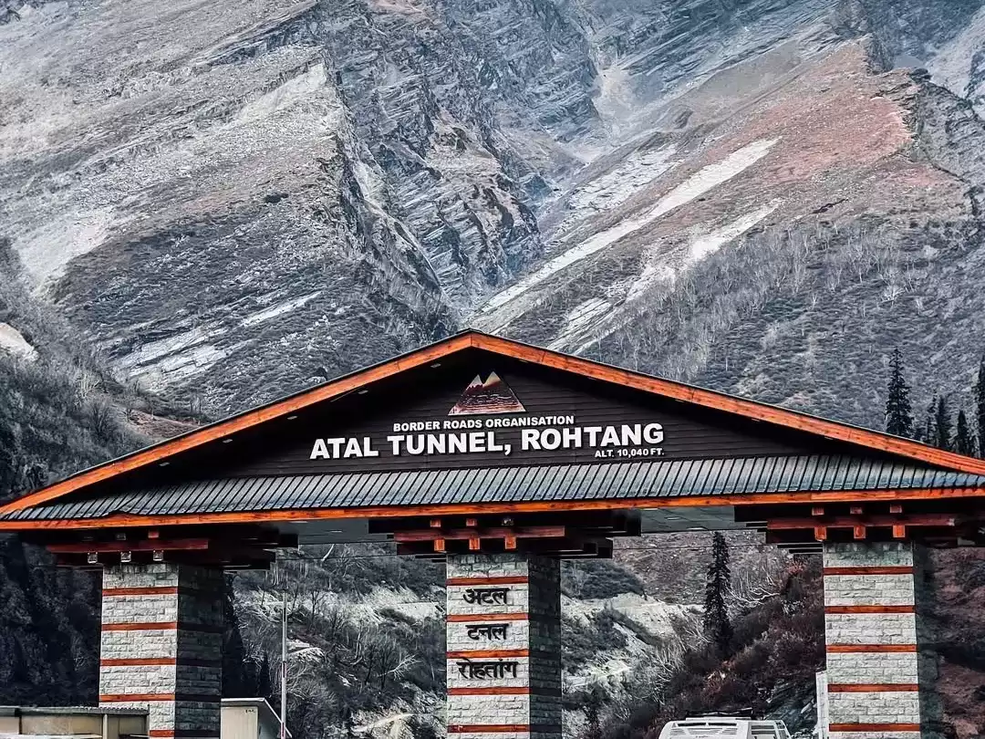 Atal Tunnel entrance gate at Rohtang in Lahaul Spiti during partly cloudy day, featuring BRO signboard, snowy mountains, perfect Manali Leh tour package.