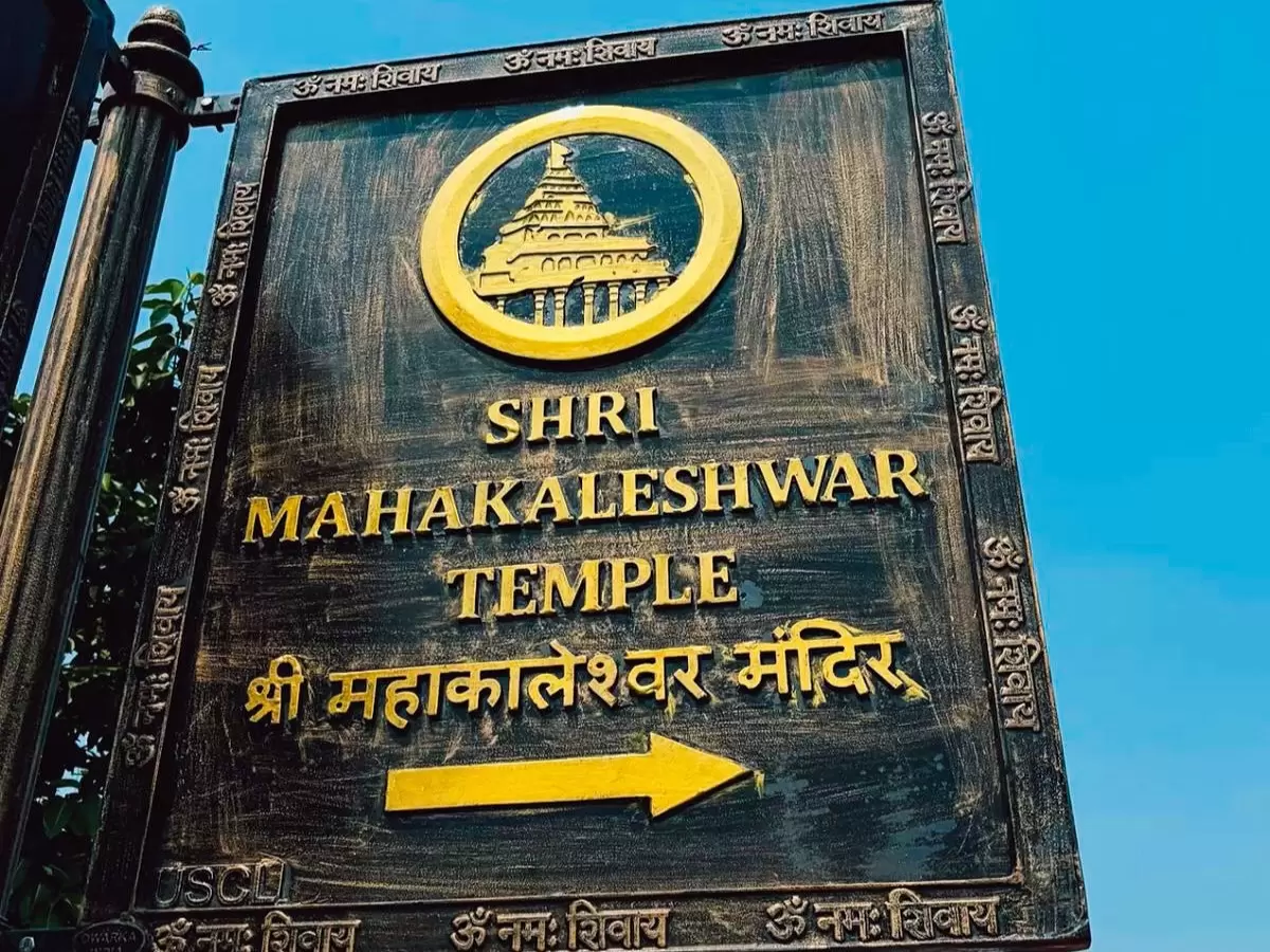 Shree Mahakaleshwar Temple signboard at Ujjain during clear daylight, featuring golden temple emblem Hindi arrow, perfect spiritual Madhya Pradesh tour package.
