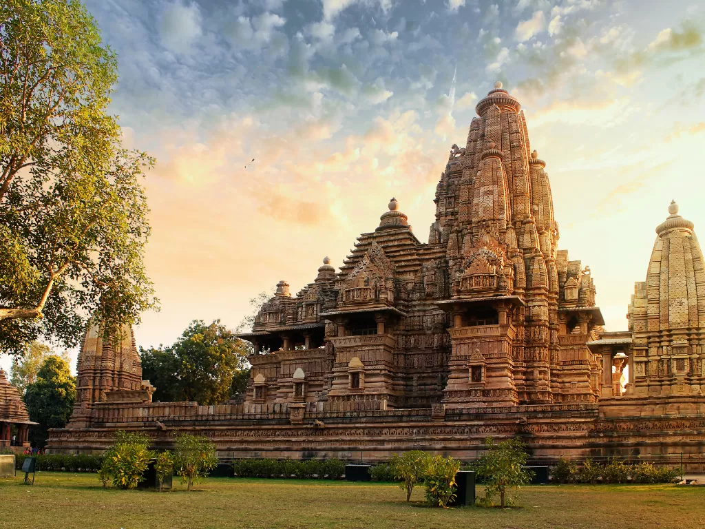 Kandariya Mahadeva Temple Khajuraho golden hour tree-framed Western Group UNESCO site, tallest Nagara shikhara 31m 84 urushringas Shiva shrine Chandela Vidyadhara 1025-1050 CE, ideal Madhya Pradesh heritage tour package.