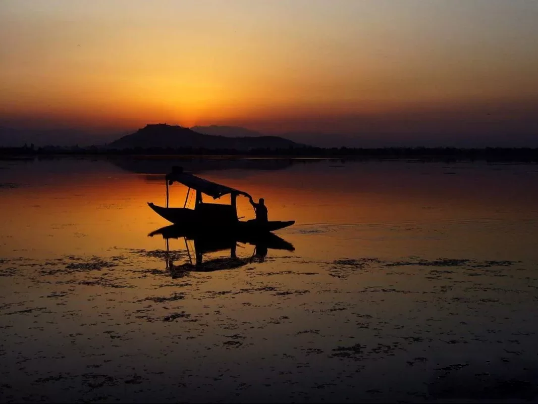 Shikara boat sunset silhouette on Dal Lake Srinagar with hill reflection featured in Kashmir Srinagar houseboat tour packages