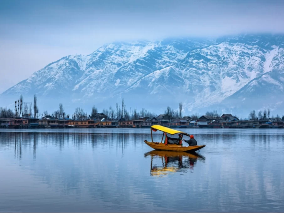 Yellow shikara boat misty morning Dal Lake Srinagar snowcapped Pir Panjal mountains houseboats reflection featured in Kashmir Srinagar tour packages