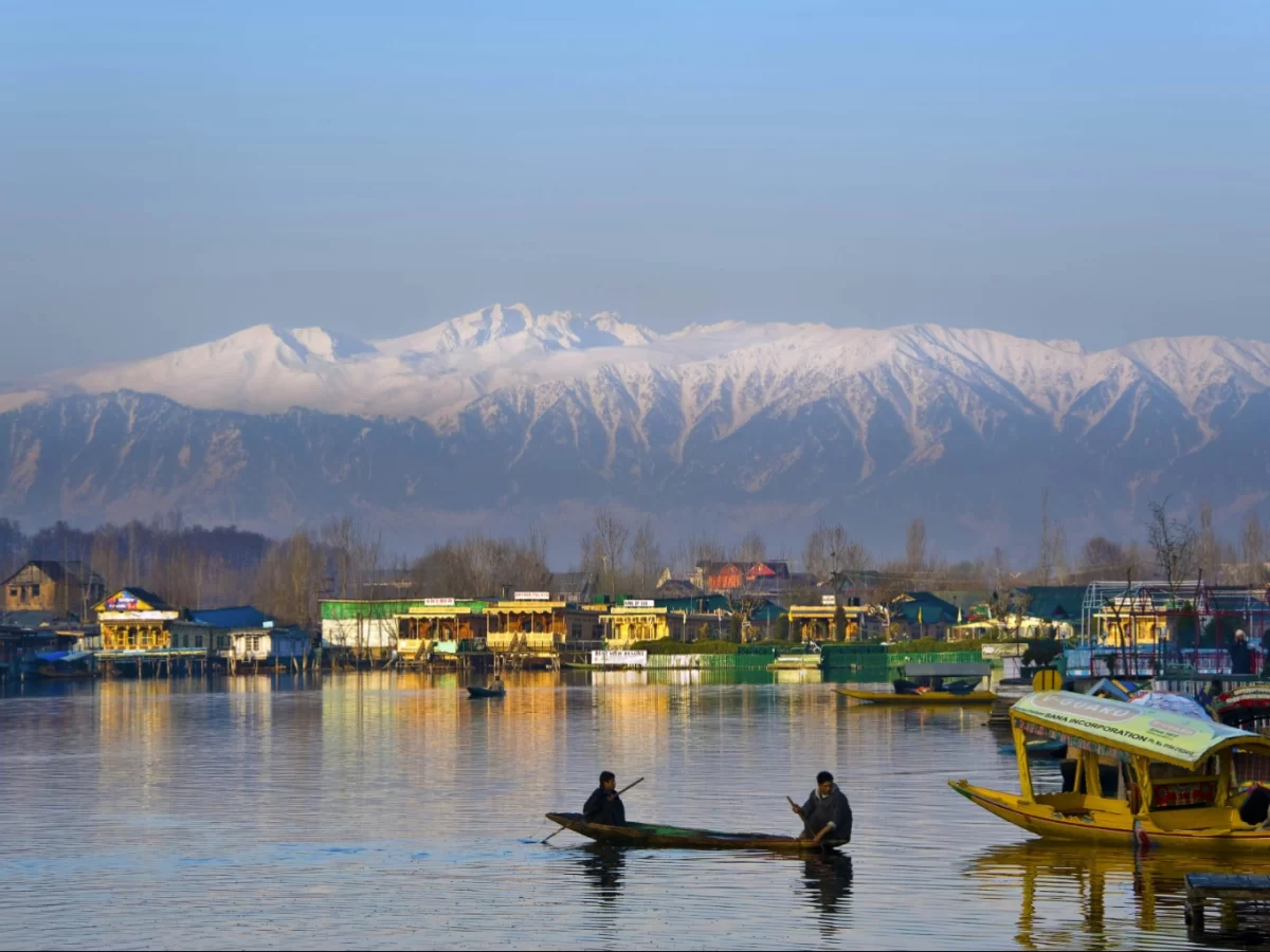 Shikara rowers golden hour Dal Lake Srinagar colorful houseboats Pir Panjal snow peaks reflection featured in Kashmir Srinagar tour packages