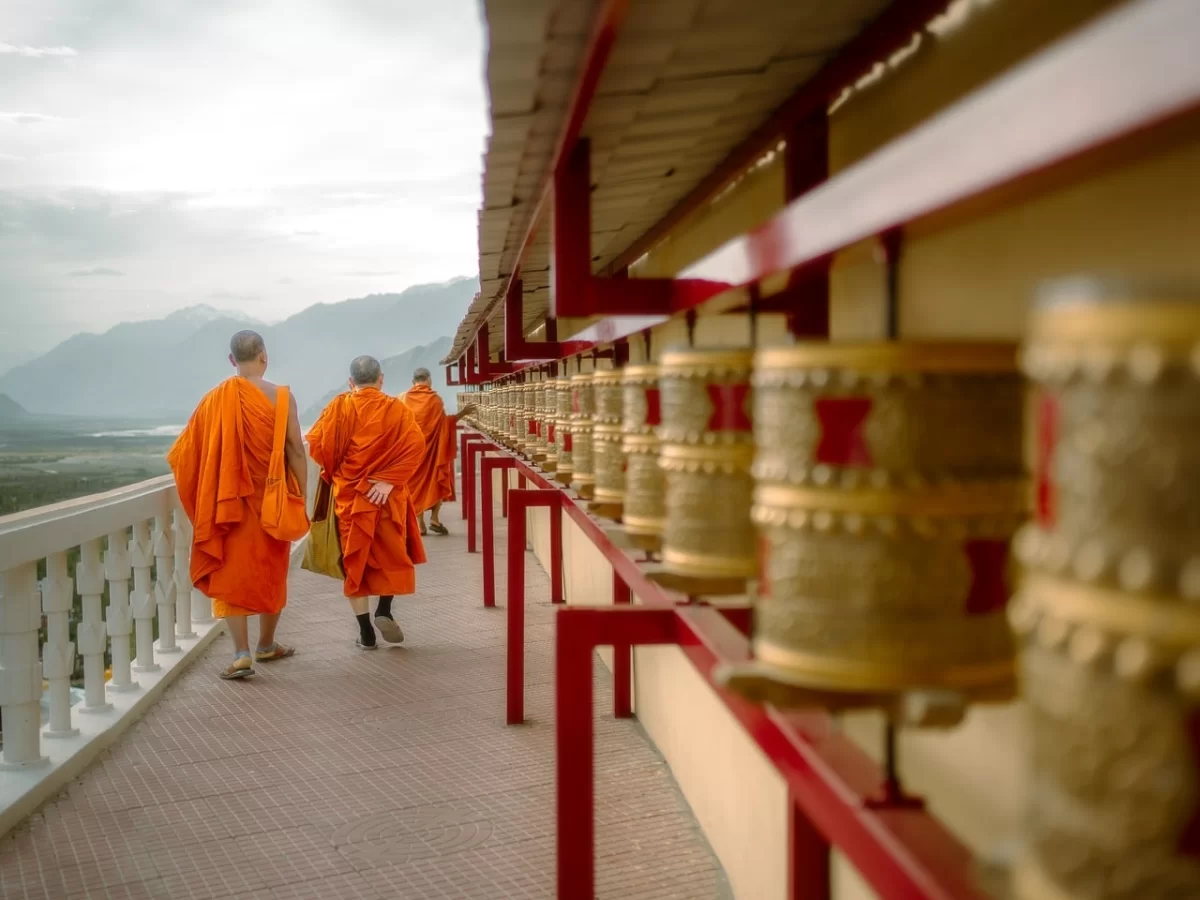 Diskit Gompa Ladakh orange robed monks prayer wheels red balcony Shyok Valley mountains Nubra backdrop, perfect Leh Ladakh spiritual adventure package.
